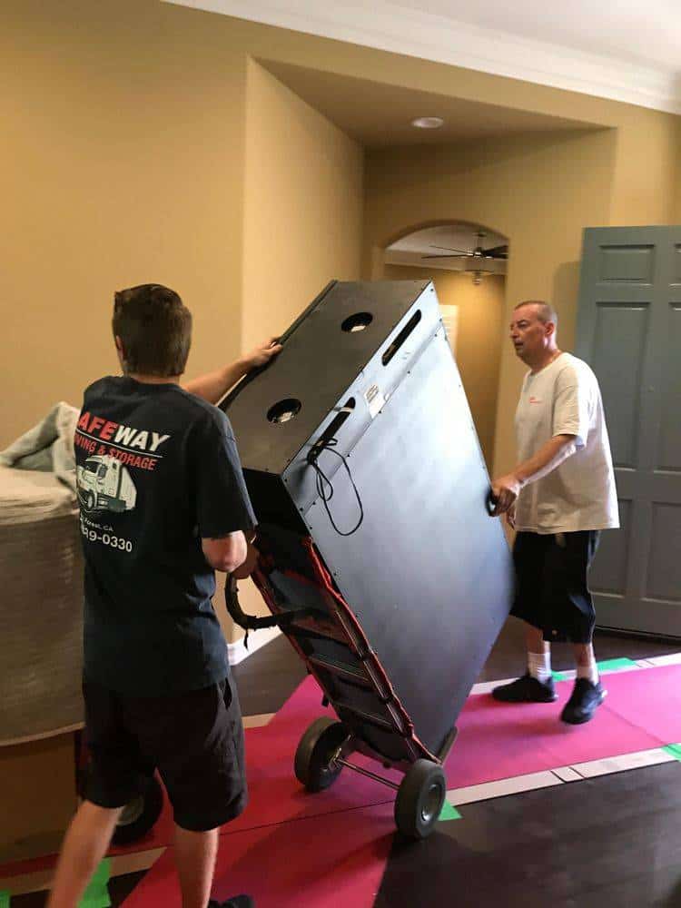 Workers carefully moving furniture on a dolly